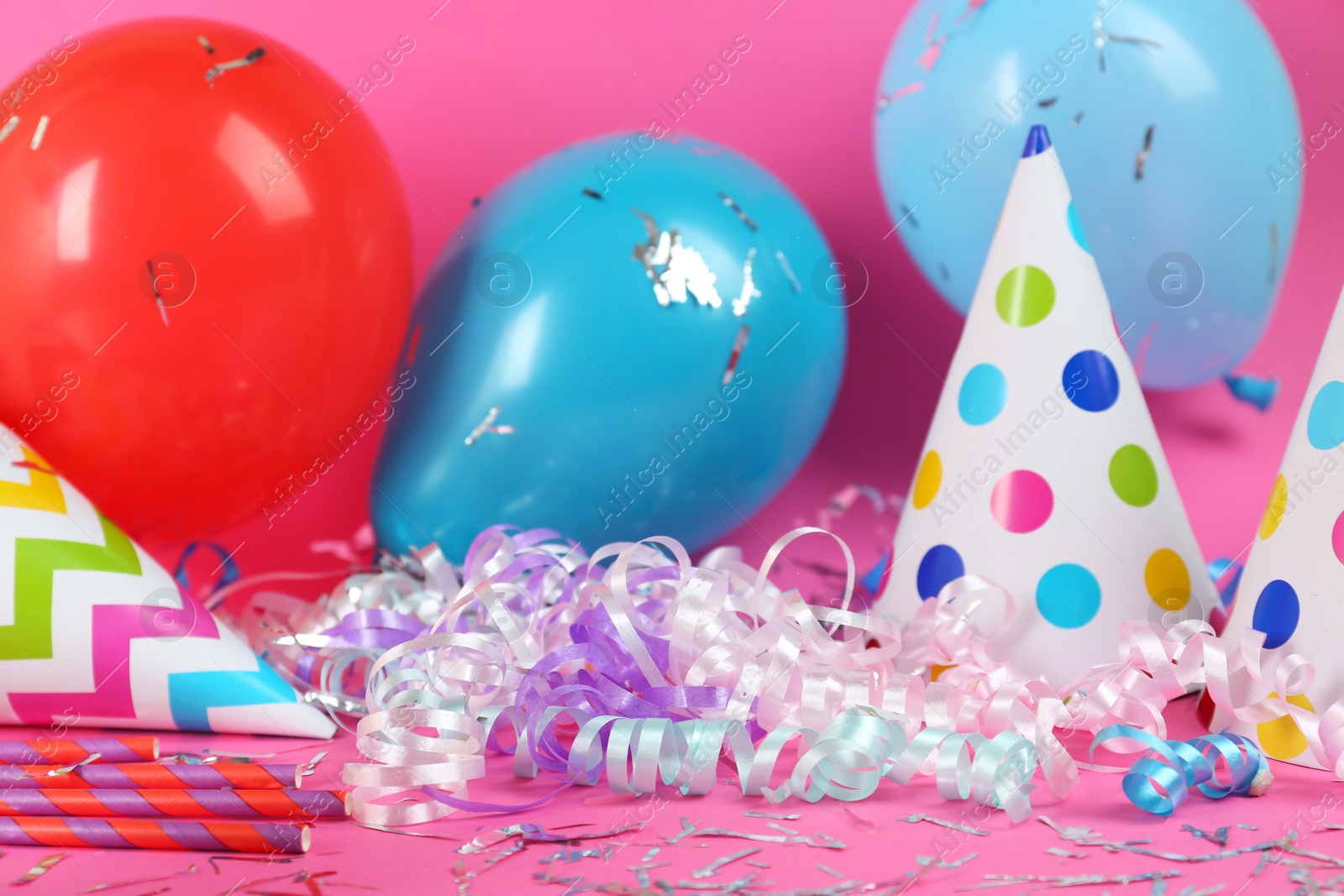 Photo of Colorful serpentine streamers and other party accessories on pink background