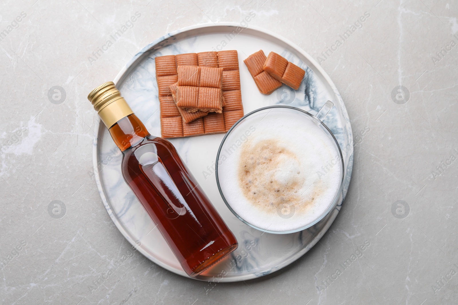 Photo of Bottle of delicious syrup, glass of coffee and caramel candies on grey table, top view