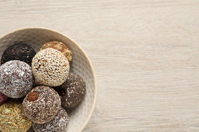 Different delicious vegan candy balls on white wooden table, top view. Space for text