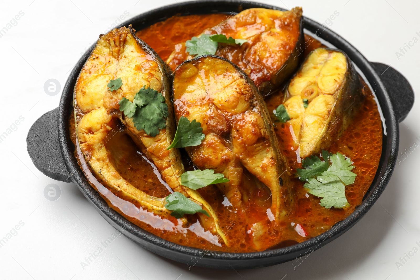 Photo of Tasty fish curry on white table, closeup. Indian cuisine