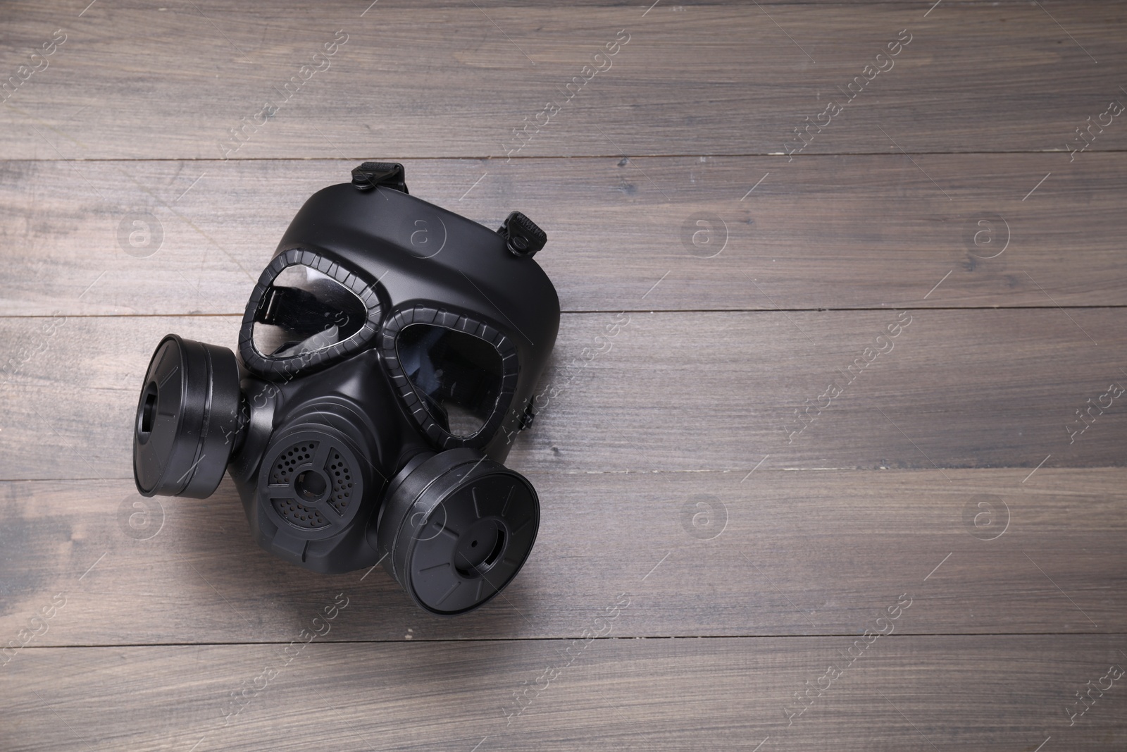 Photo of One gas mask on wooden background, top view. Space for text