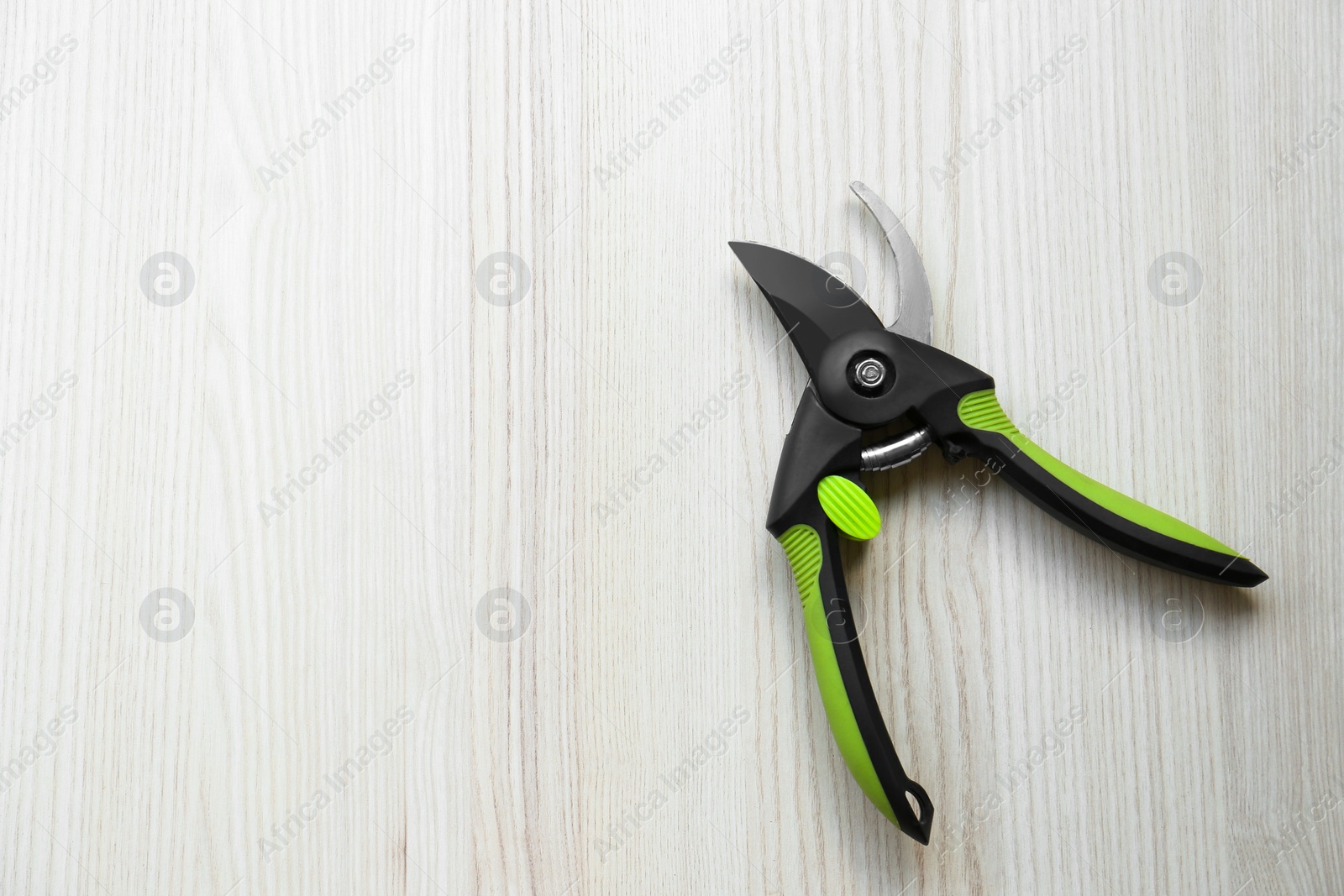 Photo of Secateur on wooden table, top view. Space for text