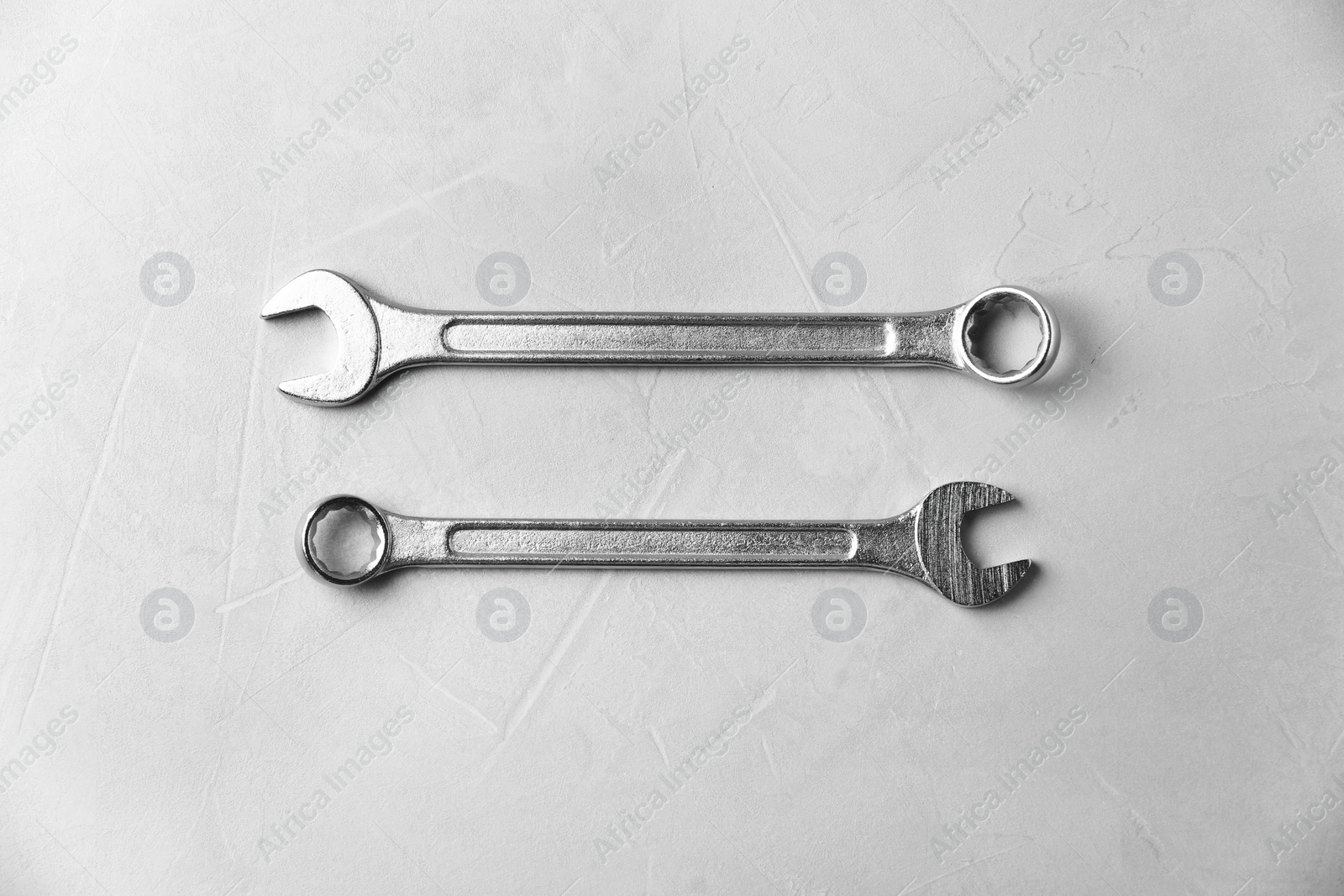 Photo of New wrenches on grey background, top view. Plumber tools