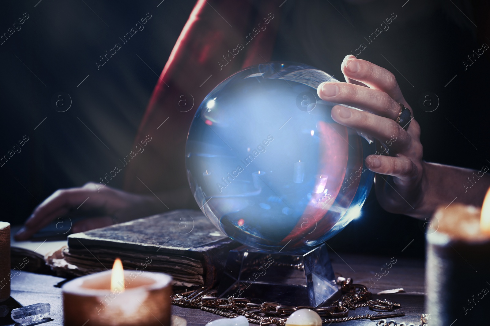 Photo of Soothsayer using crystal ball to predict future at table in darkness, closeup. Fortune telling