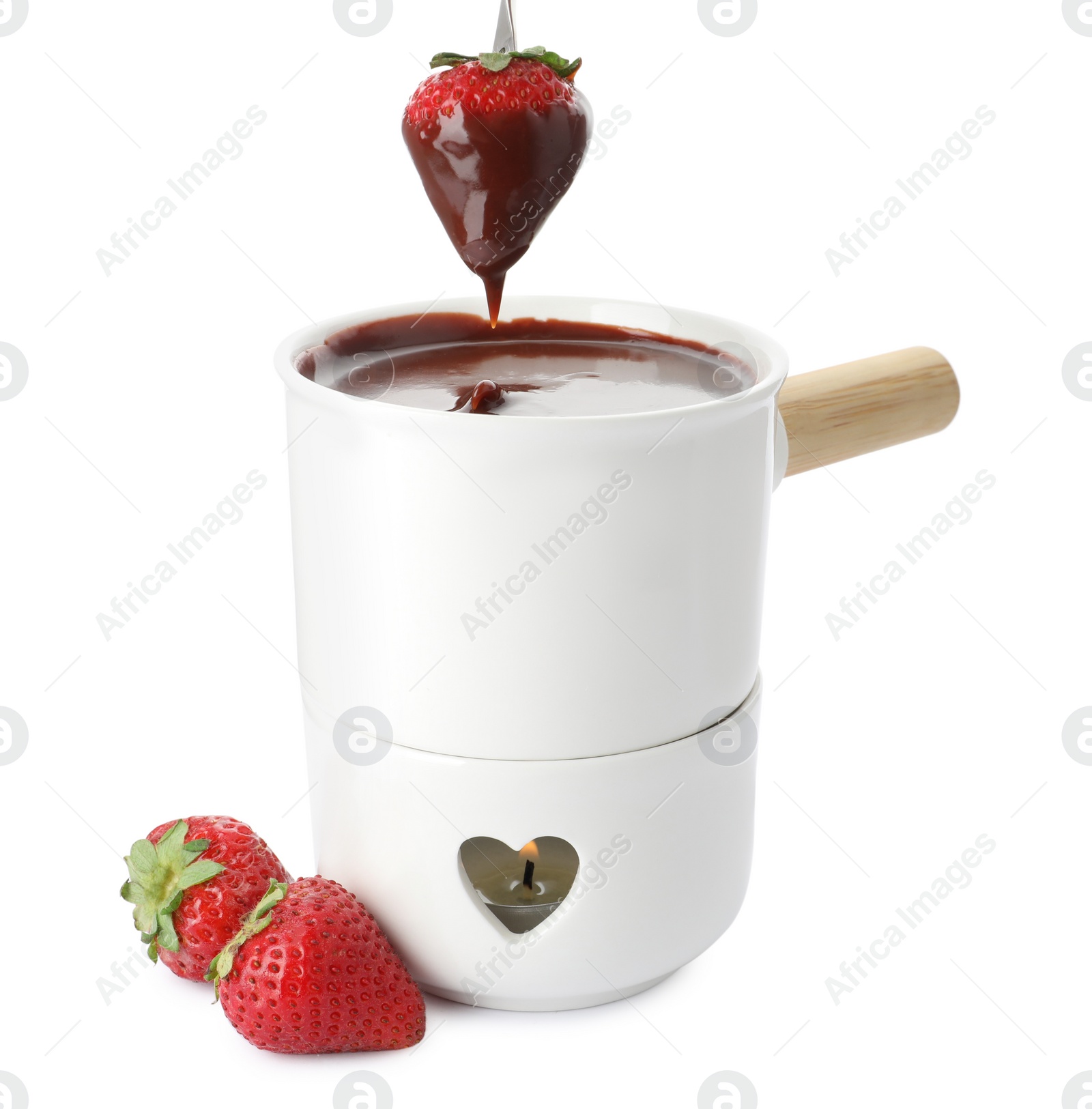 Photo of Dipping strawberry into fondue pot with chocolate on white background