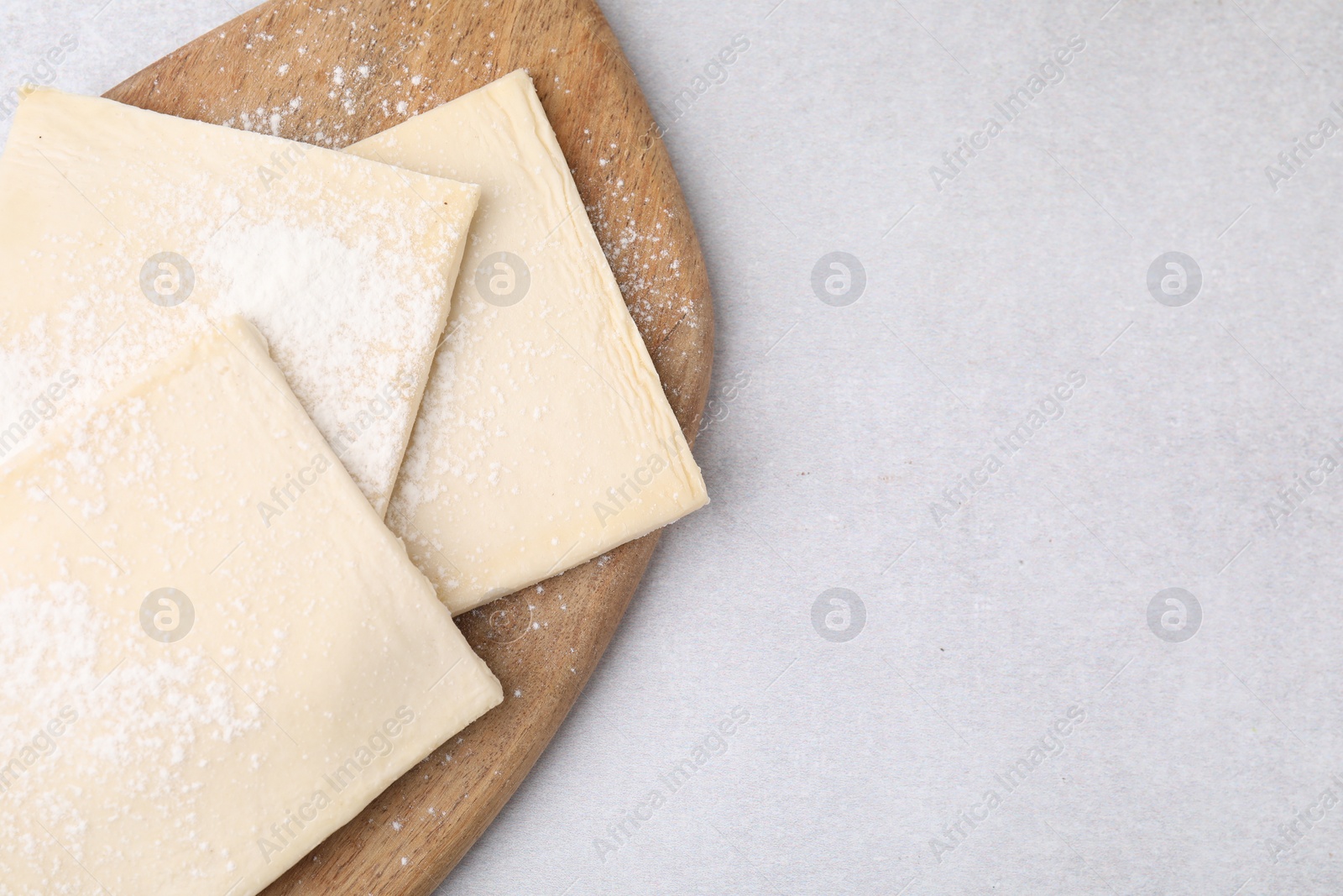 Photo of Raw puff pastry dough on white table, top view. Space for text