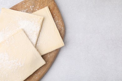 Photo of Raw puff pastry dough on white table, top view. Space for text