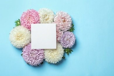 Beautiful aster flowers with sheet of paper on color background, top view. Space for text