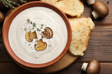 Fresh homemade mushroom soup in ceramic bowl on wooden table, flat lay