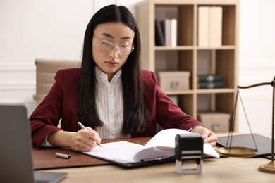 Photo of Notary signing document at table in office