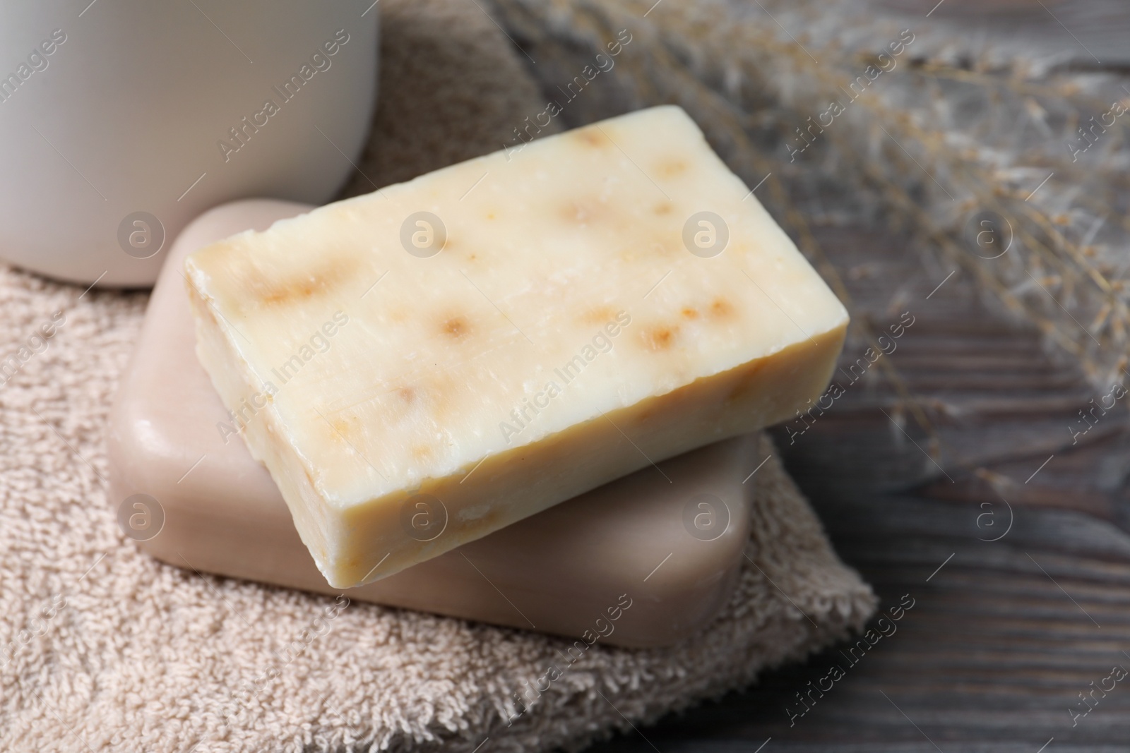 Photo of Soap bars and terry towels on wooden table, closeup