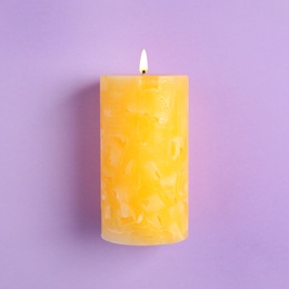 Alight scented wax candle on color background