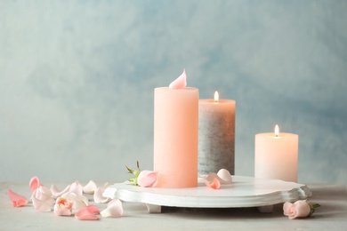 Candles with floral decor on table against color background