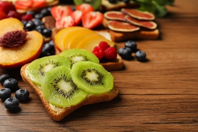 Photo of Tasty toast with butter and kiwi slices on wooden table, closeup. Space for text