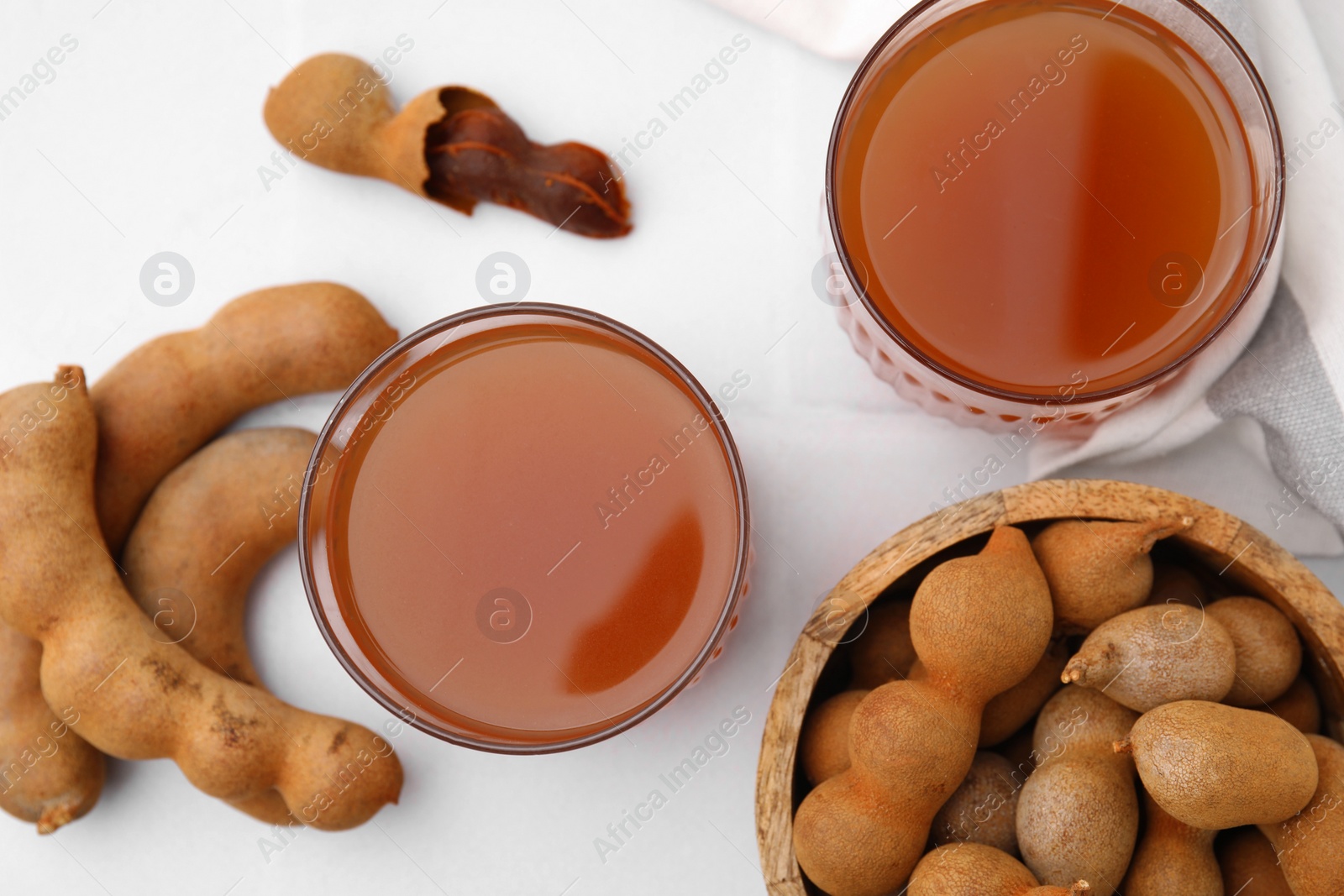 Photo of Tamarind juice and fresh fruits on white table, flat lay