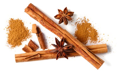 Photo of Dry aromatic cinnamon sticks, powder and anise stars isolated on white, top view