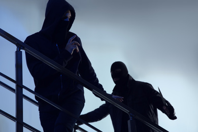 Men in masks with knife on stairs indoors. Dangerous criminals