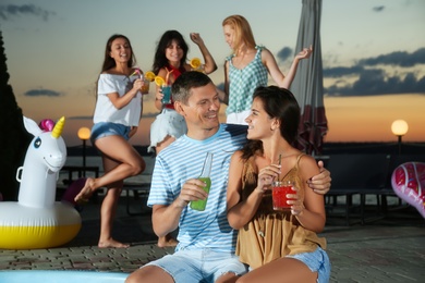 Group of happy people enjoying fun outdoor party in evening