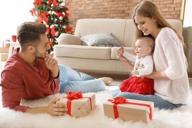 Photo of Happy couple with baby celebrating Christmas together at home