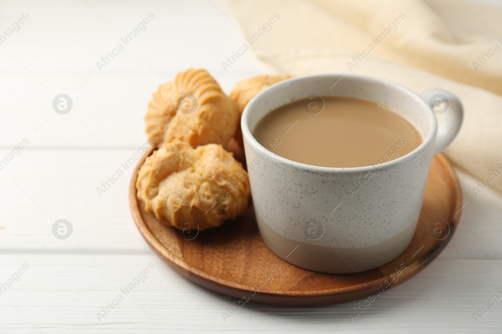 Photo of Aromatic coffee in cup and tasty profiteroles on white wooden table