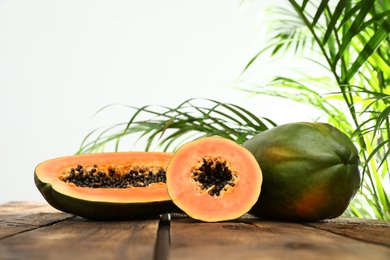 Fresh juicy papayas on wooden table against blurred background, space for text