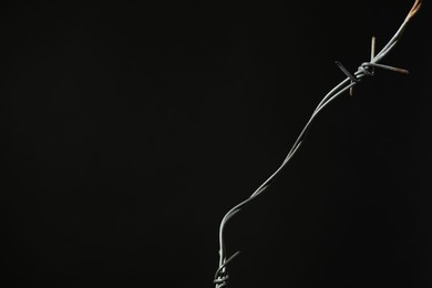 Photo of Metal barbed wire on black background. Space for text