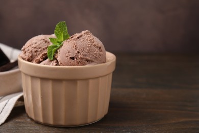 Photo of Bowl of tasty chocolate ice cream on wooden table, closeup. Space for text