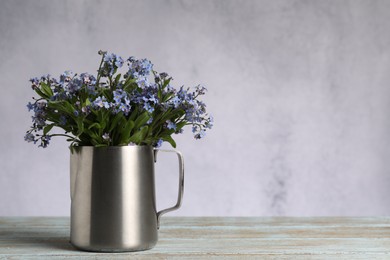 Photo of Beautiful forget-me-not flowers on wooden rustic table against light background, closeup. Space for text