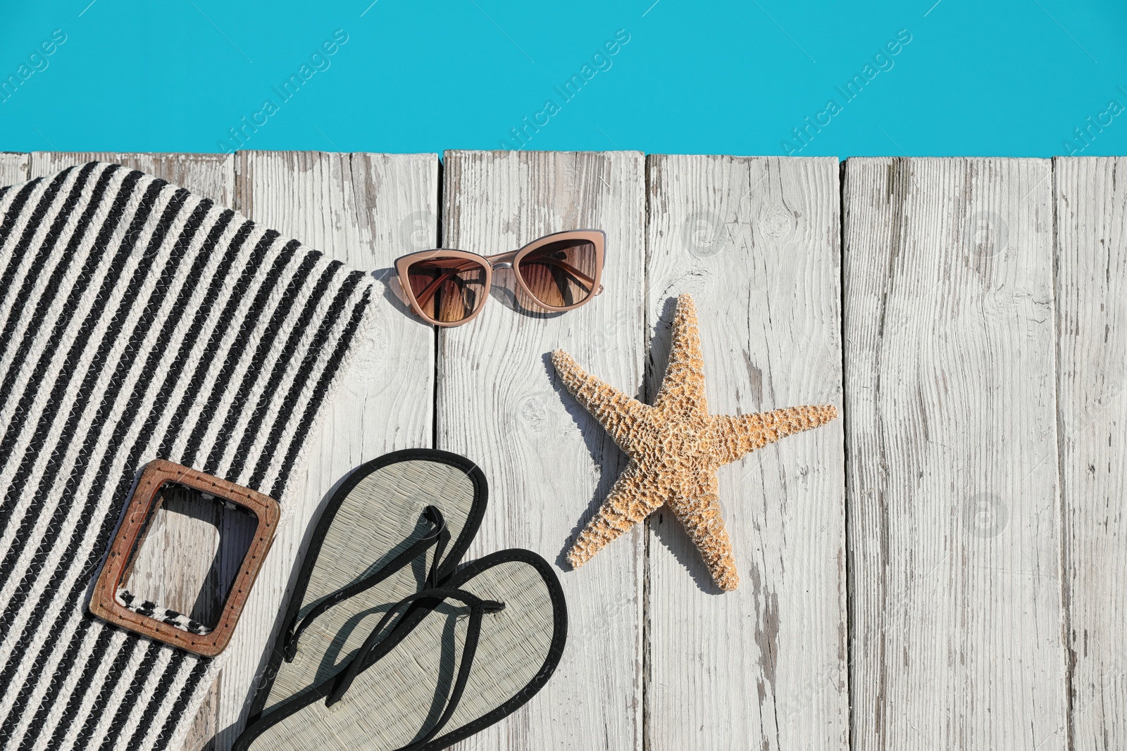 Photo of Beach accessories on wooden deck near outdoor swimming pool, flat lay. Space for text