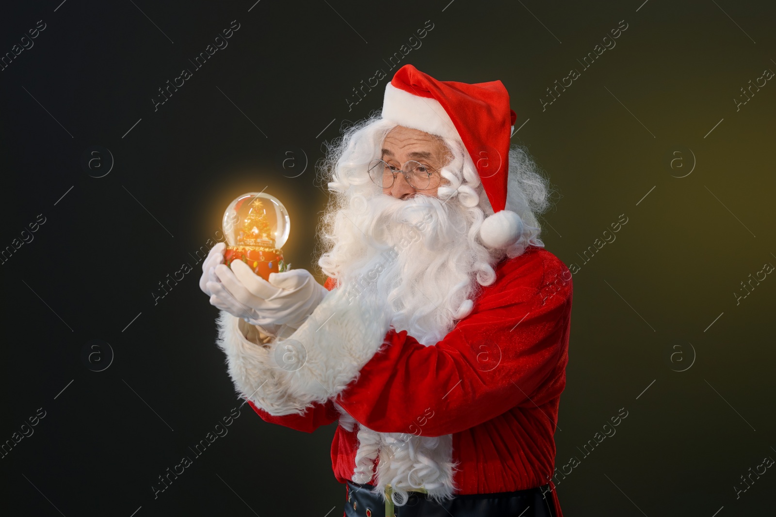 Photo of Merry Christmas. Santa Claus with snow globe on dark background