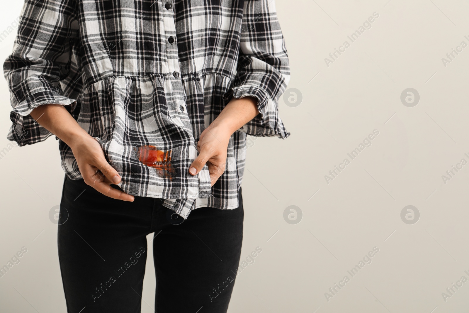 Photo of Woman showing sauce stain on her shirt against white background, closeup. Space for text