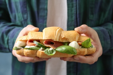 Photo of Man holding tasty croissant sandwich, closeup