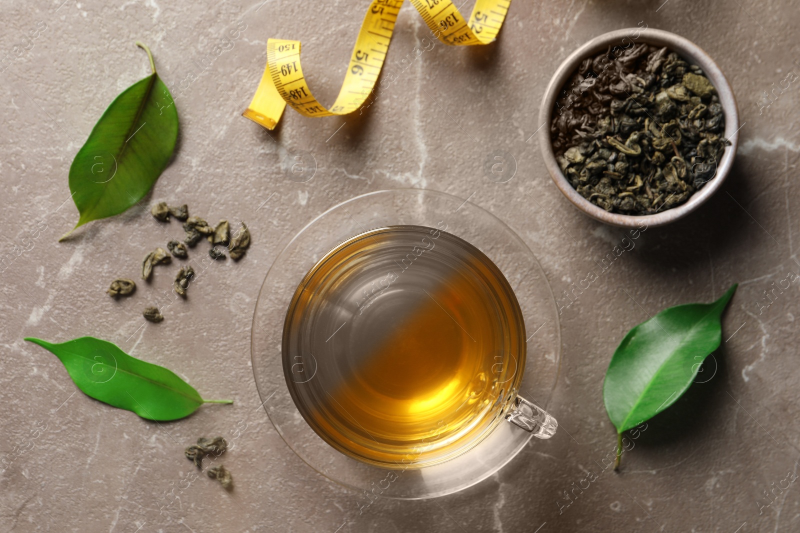 Photo of Flat lay composition with herbal diet tea and measuring tape on brown marble table. Weight loss concept