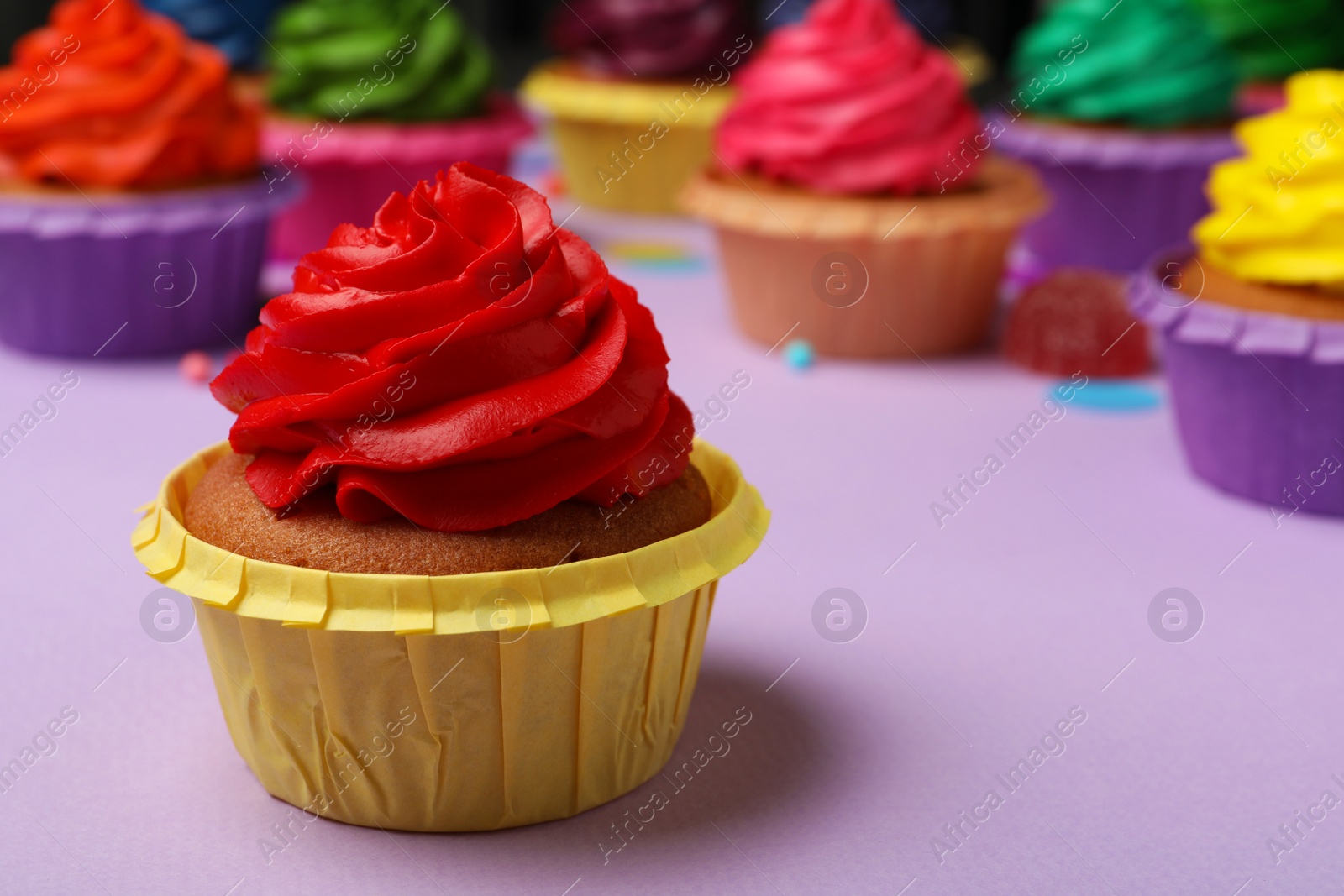 Photo of Delicious cupcake with red cream on violet table, space for text