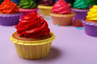 Delicious cupcake with red cream on violet table, space for text