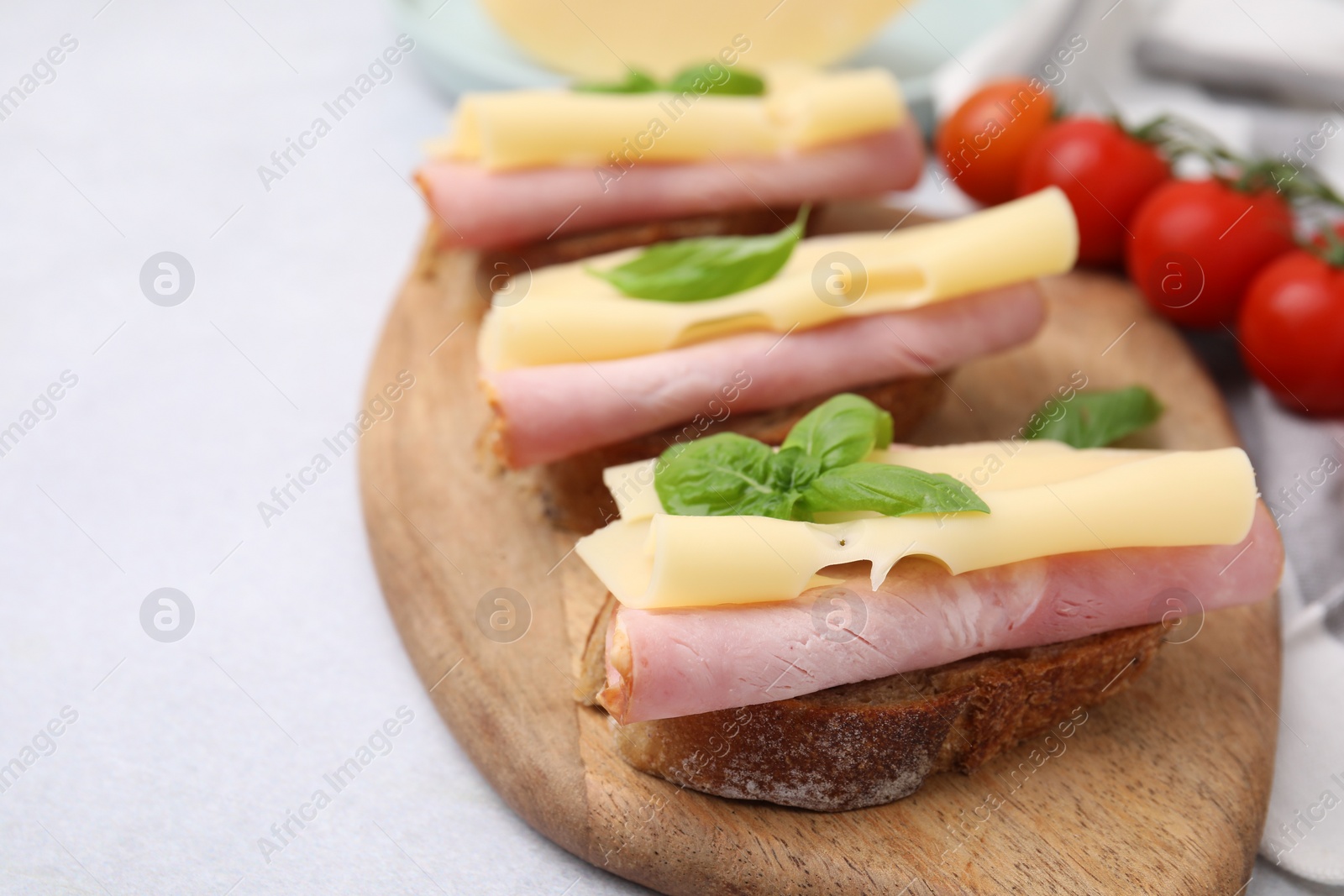 Photo of Delicious sandwiches with ham and cheese on light table, closeup. Space for text