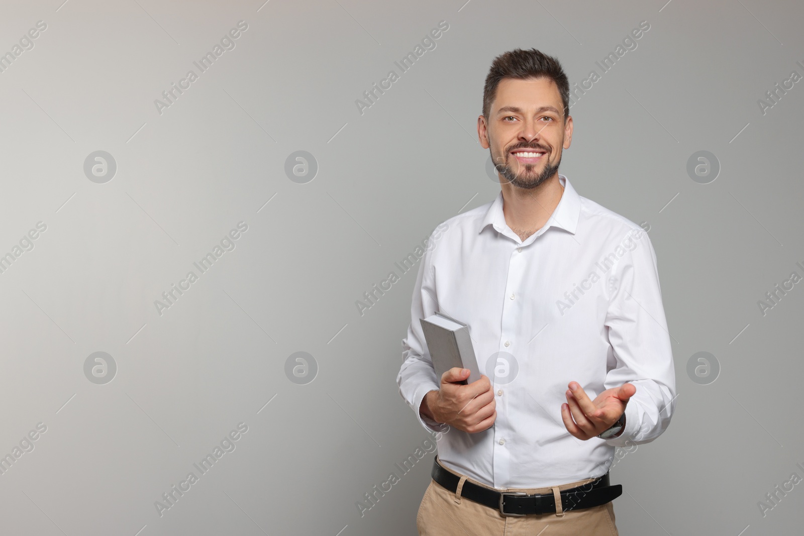 Photo of Happy teacher with book against beige background