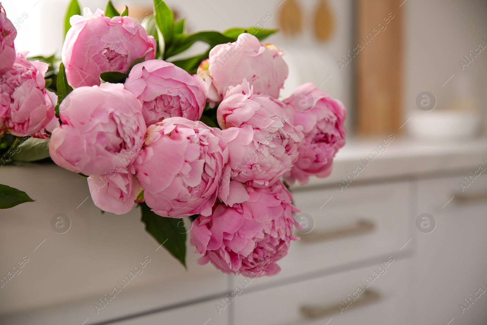 Photo of Bouquet of beautiful pink peonies on counter in kitchen, closeup