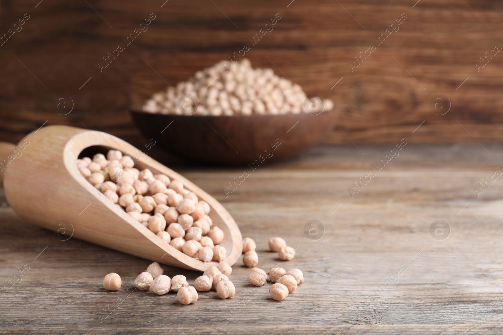 Photo of Scoop with chickpeas on wooden table. Space for text