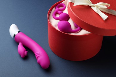 Photo of Pink sex toys and gift box on dark blue background