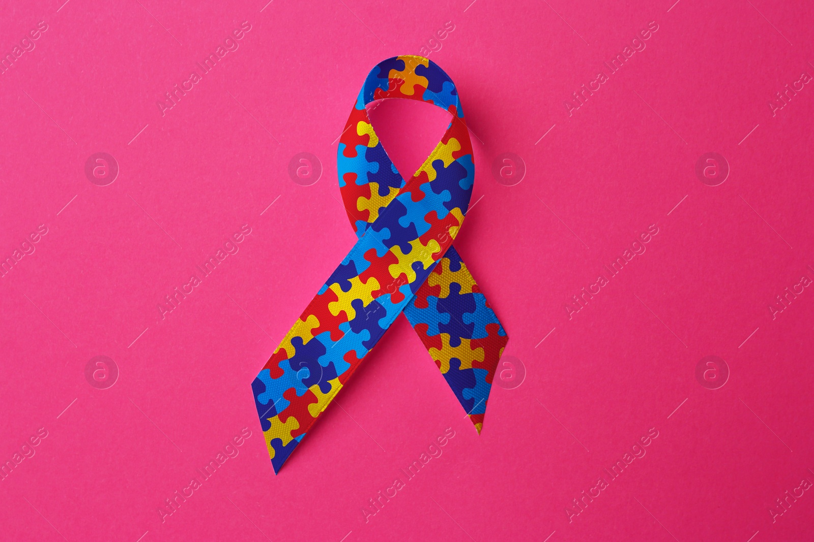 Image of World Autism Awareness Day. Colorful puzzle ribbon on pink background, top view