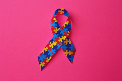 Image of World Autism Awareness Day. Colorful puzzle ribbon on pink background, top view