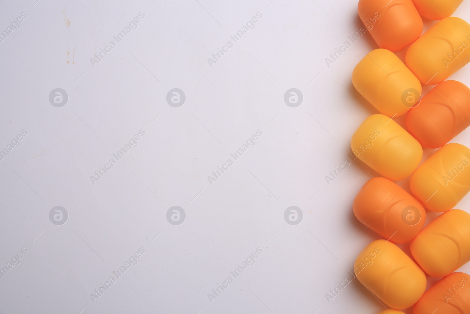 Photo of Sveti Vlas, Bulgaria - June 30, , 2023: Orange plastic capsules from Kinder Surprise Eggs on white background, flat lay and space for text