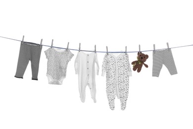 Photo of Different baby clothes and toy drying on laundry line against white background