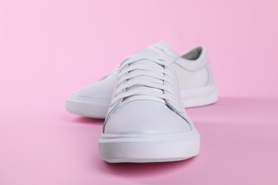 Photo of Pair of stylish white sneakers on pink background, closeup