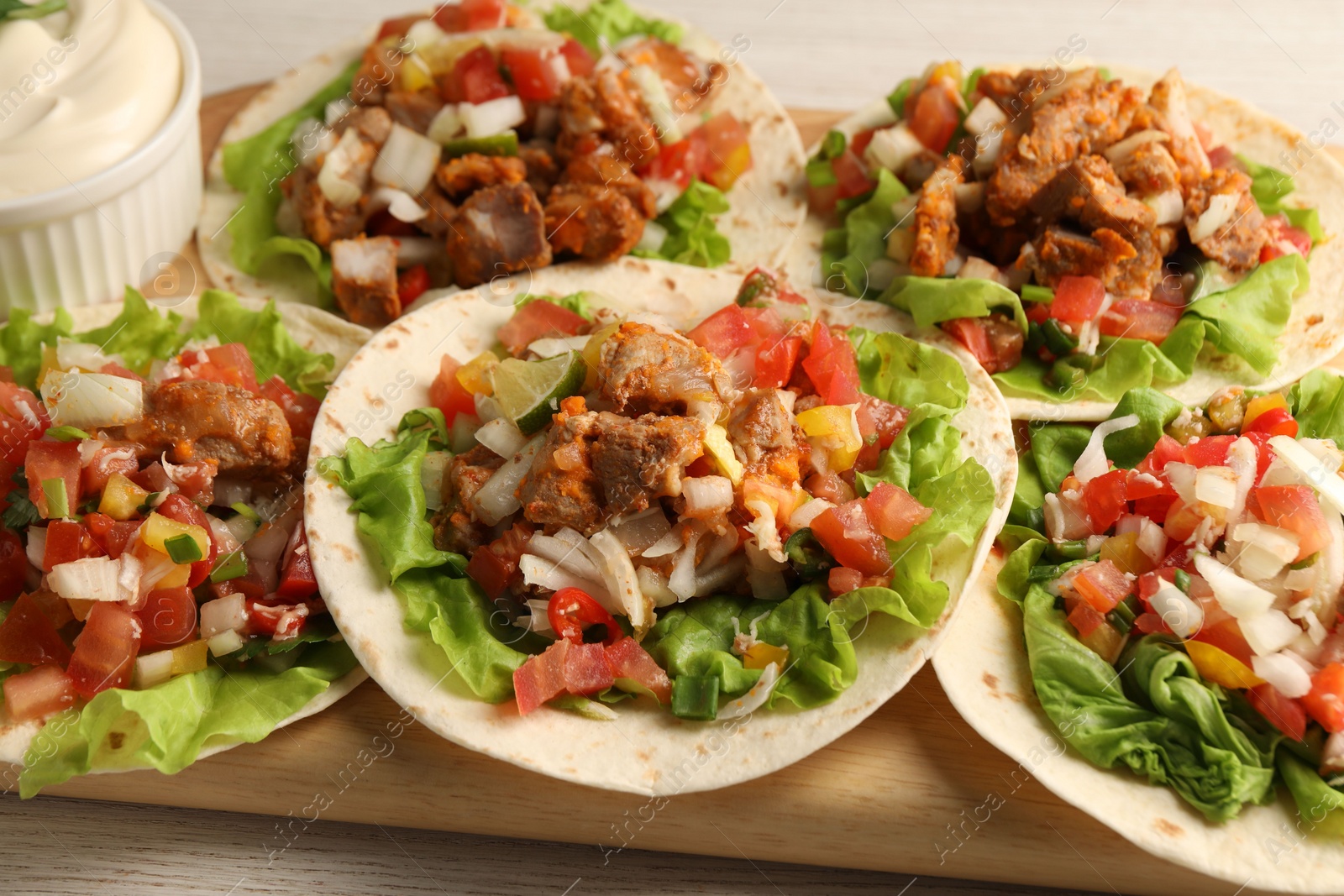 Photo of Delicious tacos with vegetables and meat on table