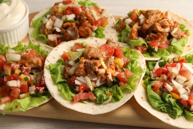 Delicious tacos with vegetables and meat on table