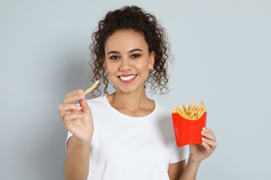 Photo of African American woman with French fries on grey background