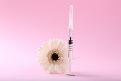 Cosmetology. Medical syringe and gerbera flower on pink background