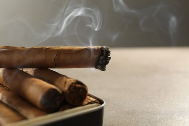 Photo of Many cigars in box on grey table, closeup. Space for text